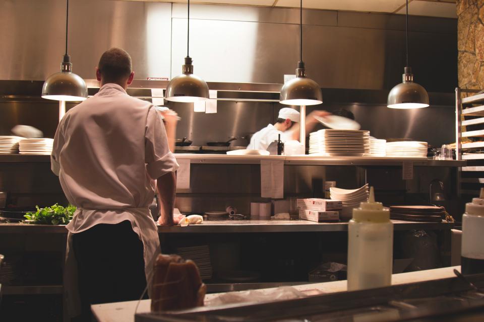 Comptoir face &agrave; la cuisine, cuisiniers au travail derri&egrave;re le passe et assiettes en attente