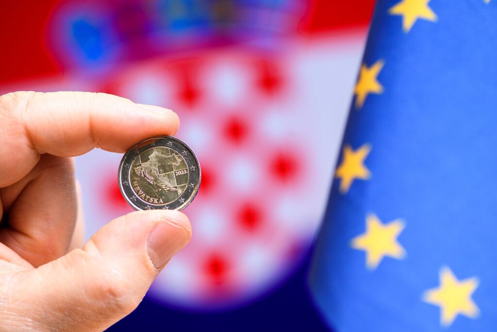 Billets et pièces en euros posés sur une surface claire à côté d'une calculatrice