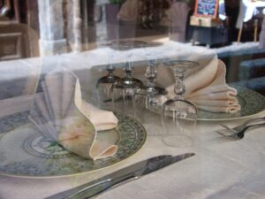 Table de restaurant dressée avec nappe blanche, couverts alignés et verres à pied