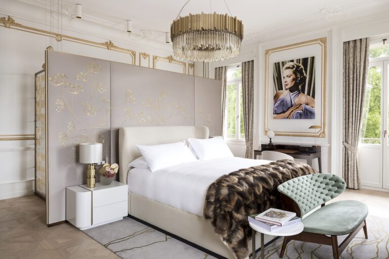Chambre d'hôtel avec lit fait au carré, fauteuil en tissu et grande fenêtre donnant sur la ville