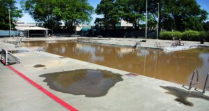 Piscine de villa vidée bordée de dalles claires et de transats sous un ciel dégagé