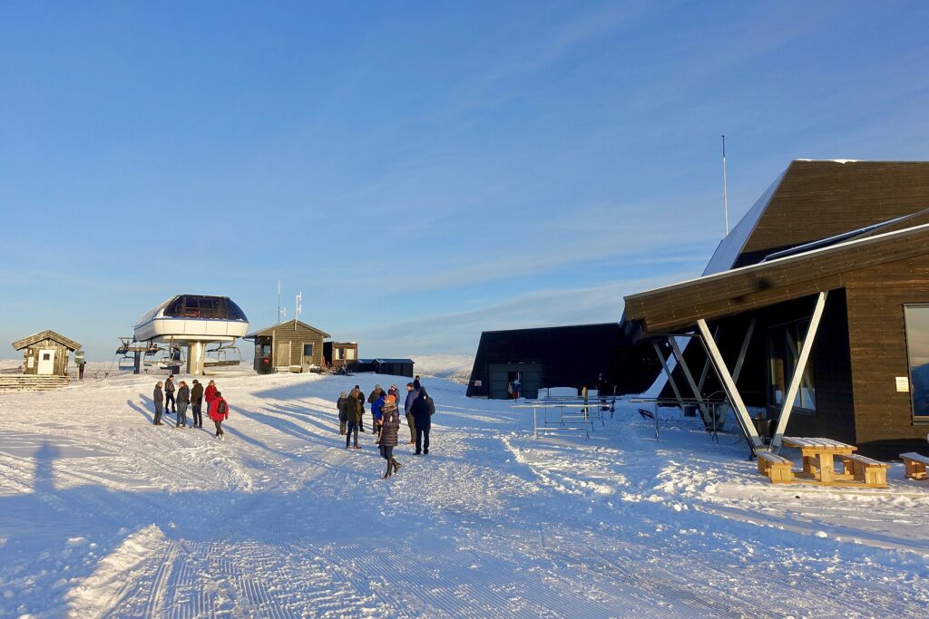 Télésiège en marche au-dessus d'une piste enneigée avec des skieurs près du départ