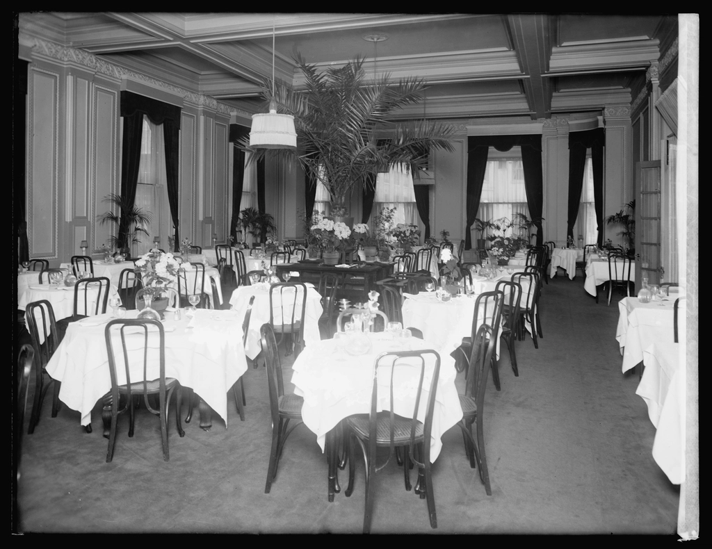 Grande table dressée dans une salle à manger d'hôtel avec chaises alignées et lustre