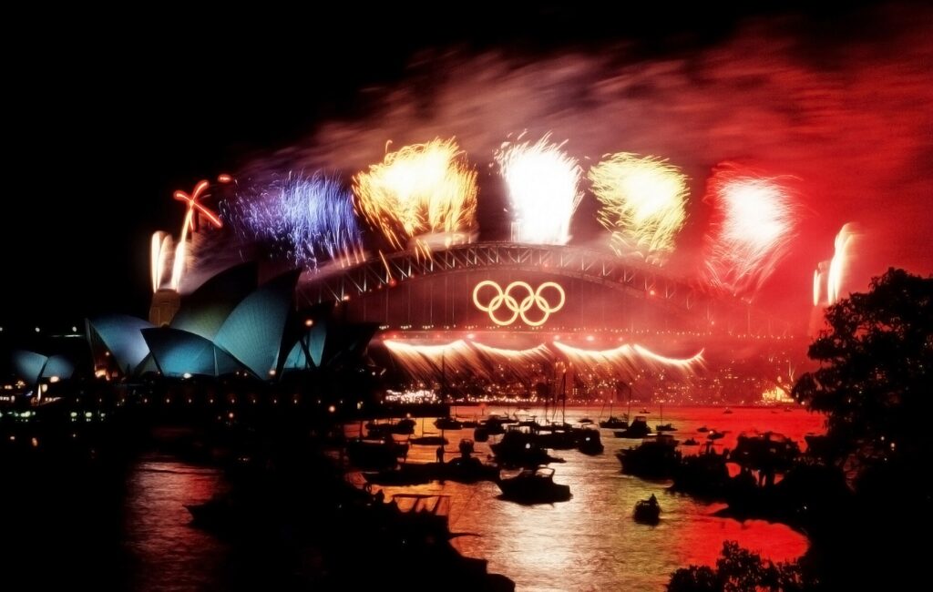 Feu d'artifice au-dessus d'un port vu depuis l'eau avec quais illumin&eacute;s