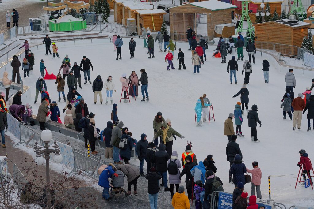 Patinoire en plein air entour&eacute;e d'immeubles illumin&eacute;s en soir&eacute;e d'hiver