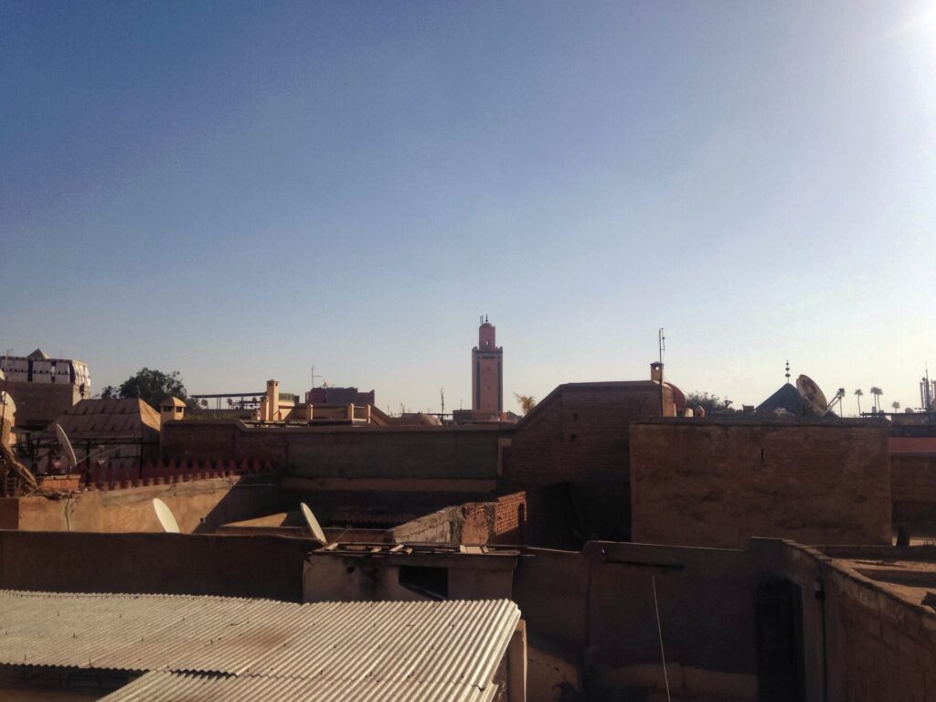 Ruelle &eacute;troite de la m&eacute;dina de Marrakech bord&eacute;e de murs ocre et de portes en bois sculpt&eacute;