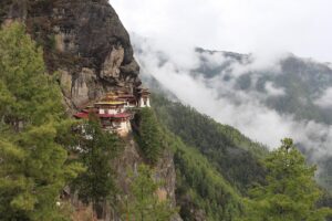 Monastère himalayen accroché à une falaise au-dessus d'une vallée boisée