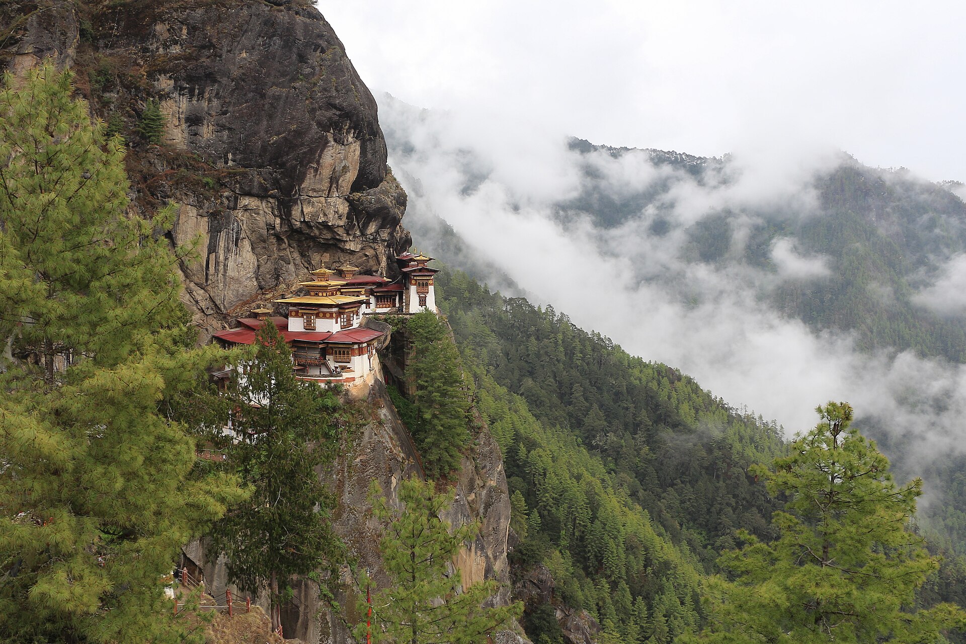 Monastère himalayen accroché à une falaise au-dessus d'une vallée boisée