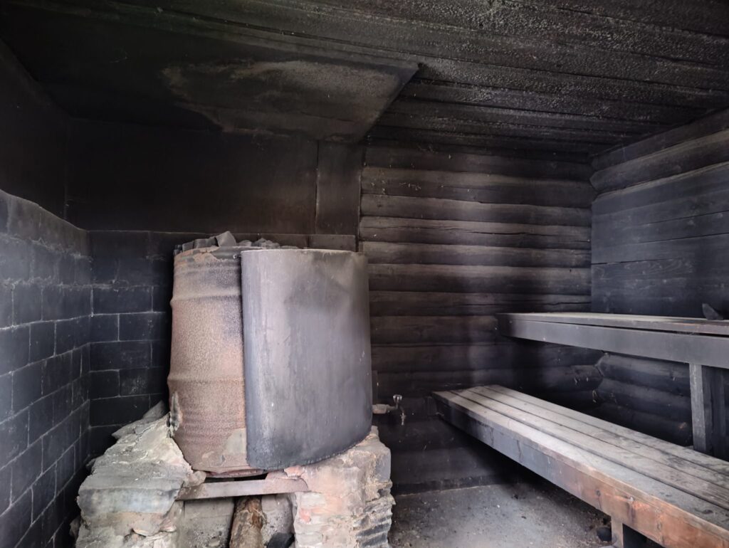 Intérieur de sauna en bois clair avec bancs étagés et poêle à pierres