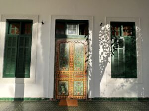 Patio intérieur d'un riad marocain avec bassin central, arcades sculptées et palmiers en pots