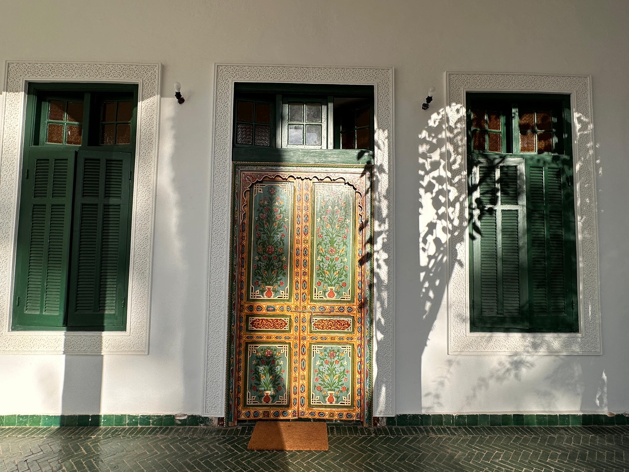 Patio intérieur d'un riad marocain avec bassin central, arcades sculptées et palmiers en pots