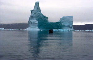 Fjord groenlandais parsemé d'icebergs bleutés sous un ciel dégagé