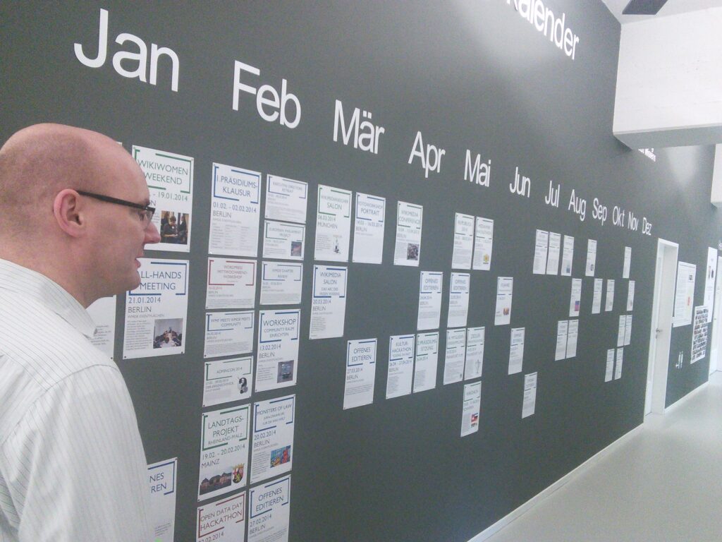 Calendrier mural annot&eacute; pos&eacute; pr&egrave;s d'un carnet ouvert et d'un stylo